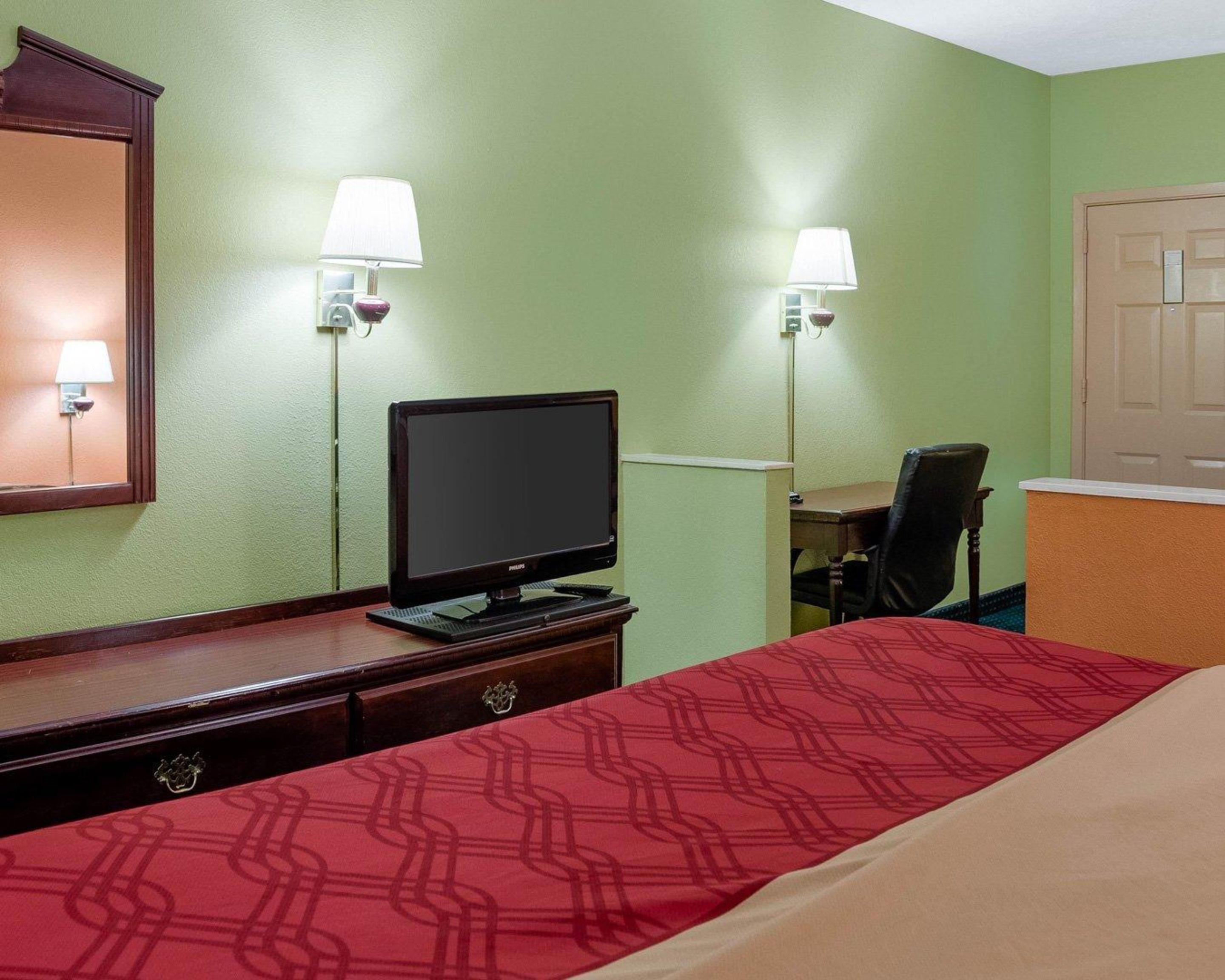 Une chambre d’hôtel équipée d’un lit, d’un bureau, d’un ordinateur et de deux lampes fixées au mur.