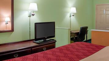 Une chambre d’hôtel équipée d’un lit, d’un bureau, d’un ordinateur et de deux lampes fixées au mur.