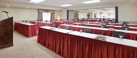 A conference room with multiple tables, a podium, and a large mirror on the wall.