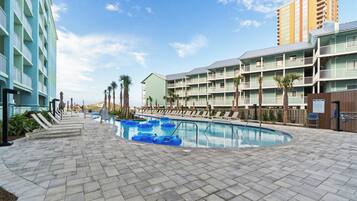 Una piscina al aire libre, sombrillas, sillones reclinables de piscina