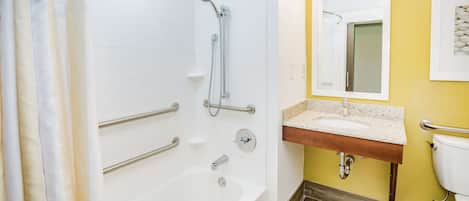 A bathroom with a bathtub, shower, and sink. There are grab bars and a mirror above the sink.