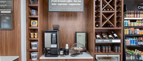 A coffee shop with a coffee machine, a display of local delights, and a wine cooler.