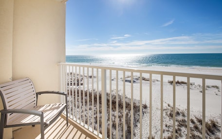 A balcony with a view of the beach and ocean.