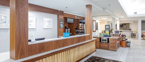 Ein Hotel-Empfangsbereich mit Holzbude, einer Minibar und einer Sitzecke mit gemustertem Teppich.