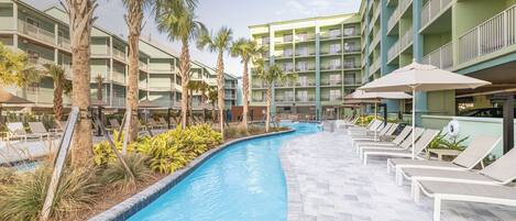 Ein Swimmingpool mit Liegestühlen und Palmen, umgeben von einem mehrstöckigen Hotelgebäude.