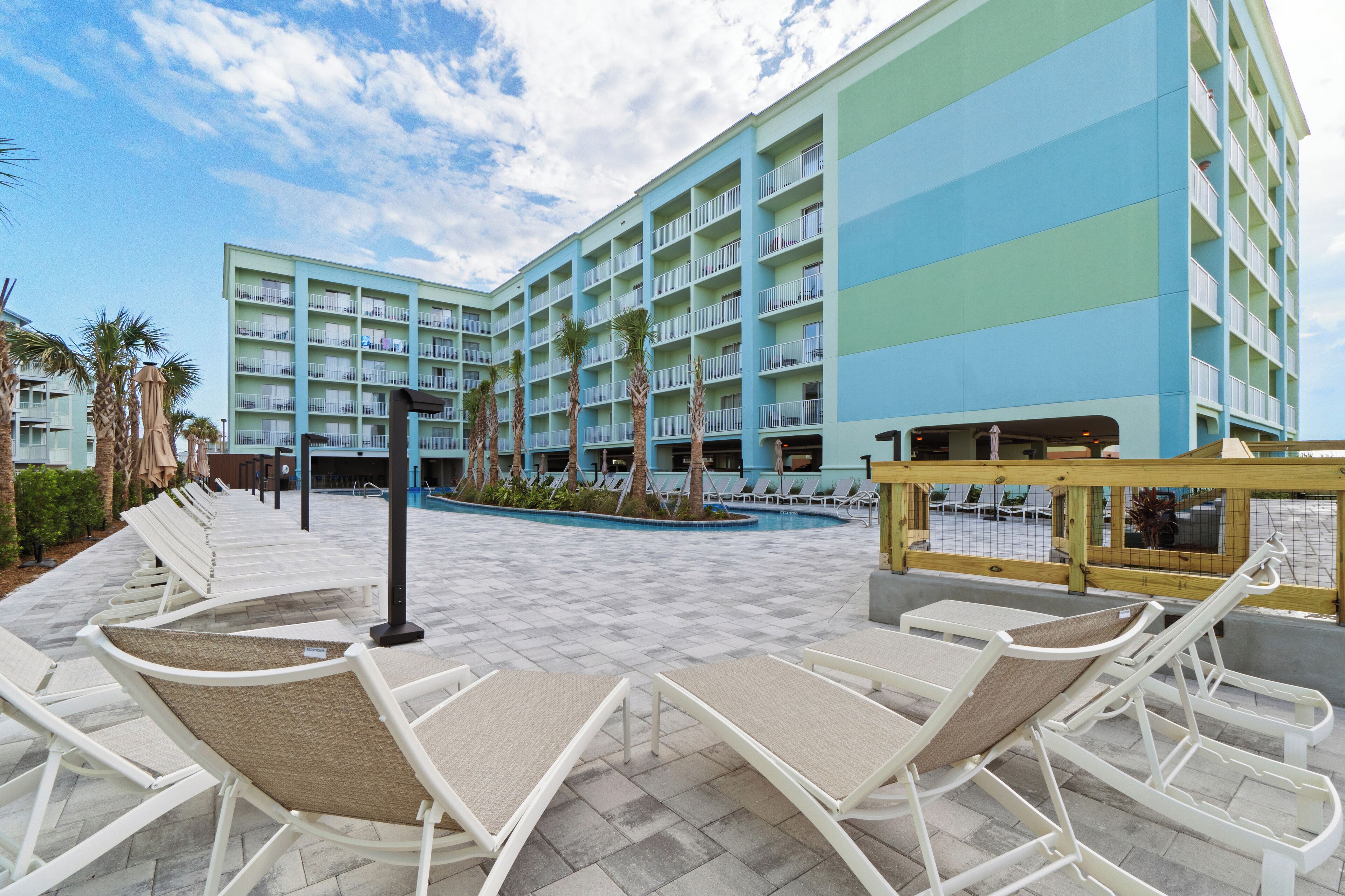 Un hôtel doté de nombreux balcons, d’une piscine et de chaises longues.