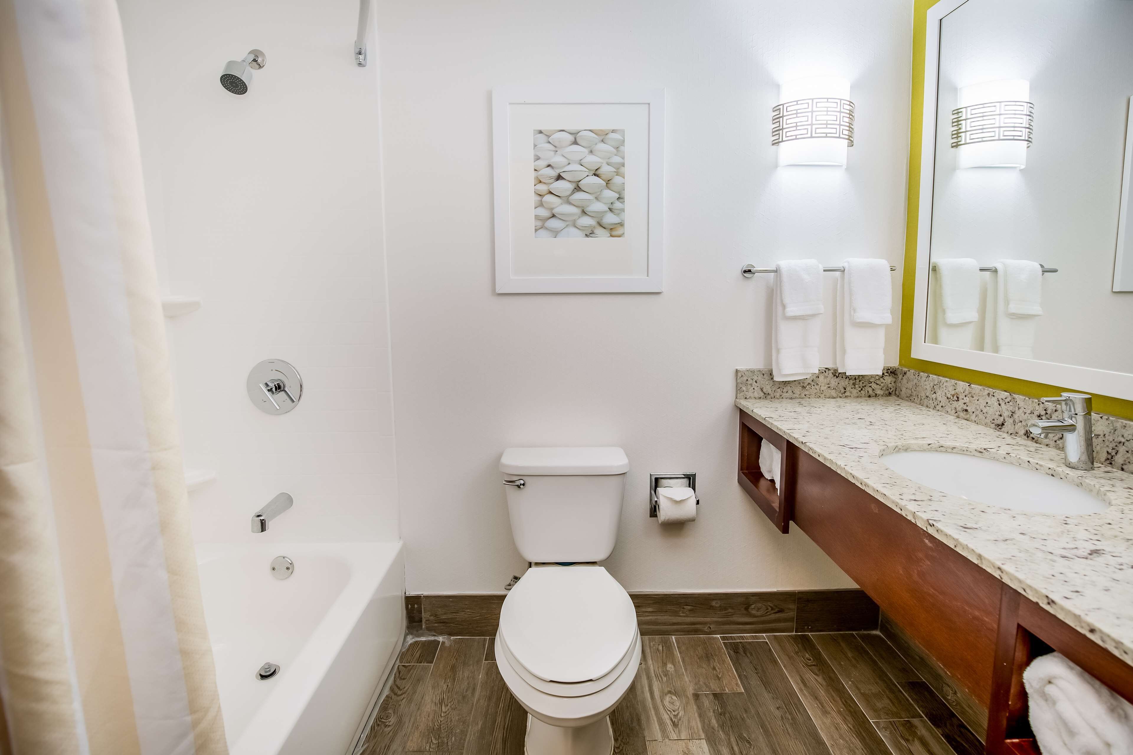 Ein Badezimmer mit Badewanne, Toilette, Waschbecken und einem gerahmten Bild an der Wand.
