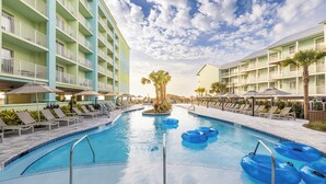 A swimming pool with lounge chairs and umbrellas, surrounded by multi-story buildings with balconies. - Hilton Garden Inn Orange Beach Beachfront (Orange Beach)