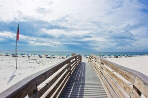 A wooden boardwalk leading to a beach with umbrellas and beach chairs. - Hilton Garden Inn Orange Beach Beachfront (Orange Beach)