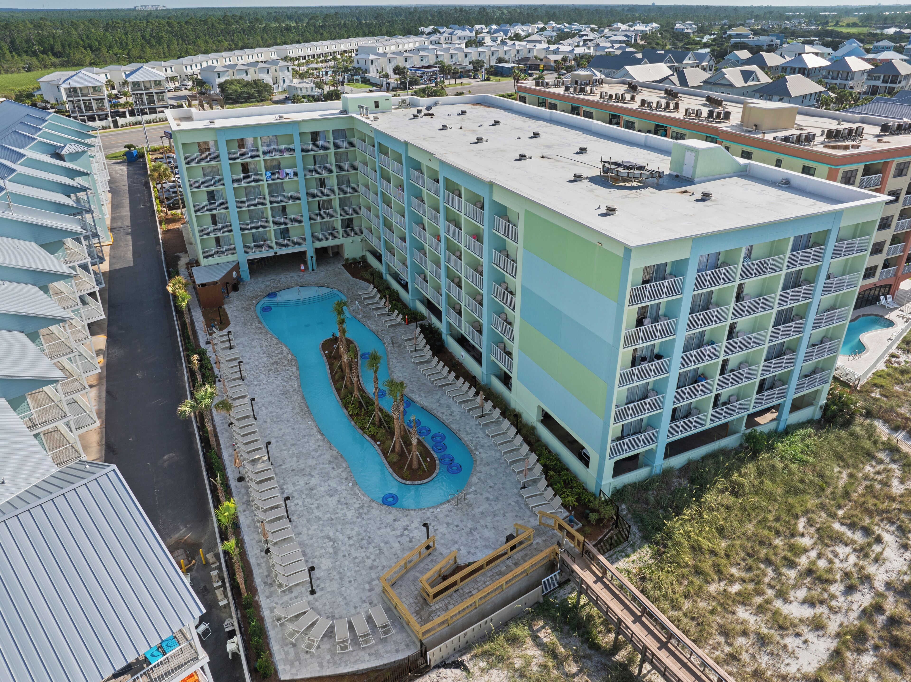 A resort with a swimming pool, multiple balconies, and a parking area.