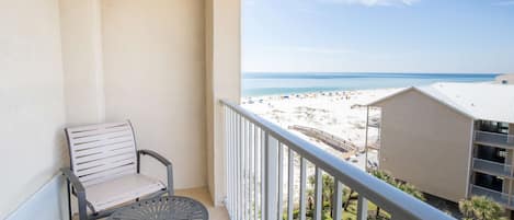 Un balcon donnant sur une plage, avec une chaise et une table.