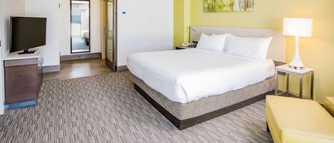 Habitación de hotel con cama, televisión, escritorio, lámpara y un cuadro en la pared.