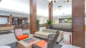 A modern lobby with a reception desk, seating area, and a coffee bar. - Hilton Garden Inn Orange Beach Beachfront (Orange Beach)