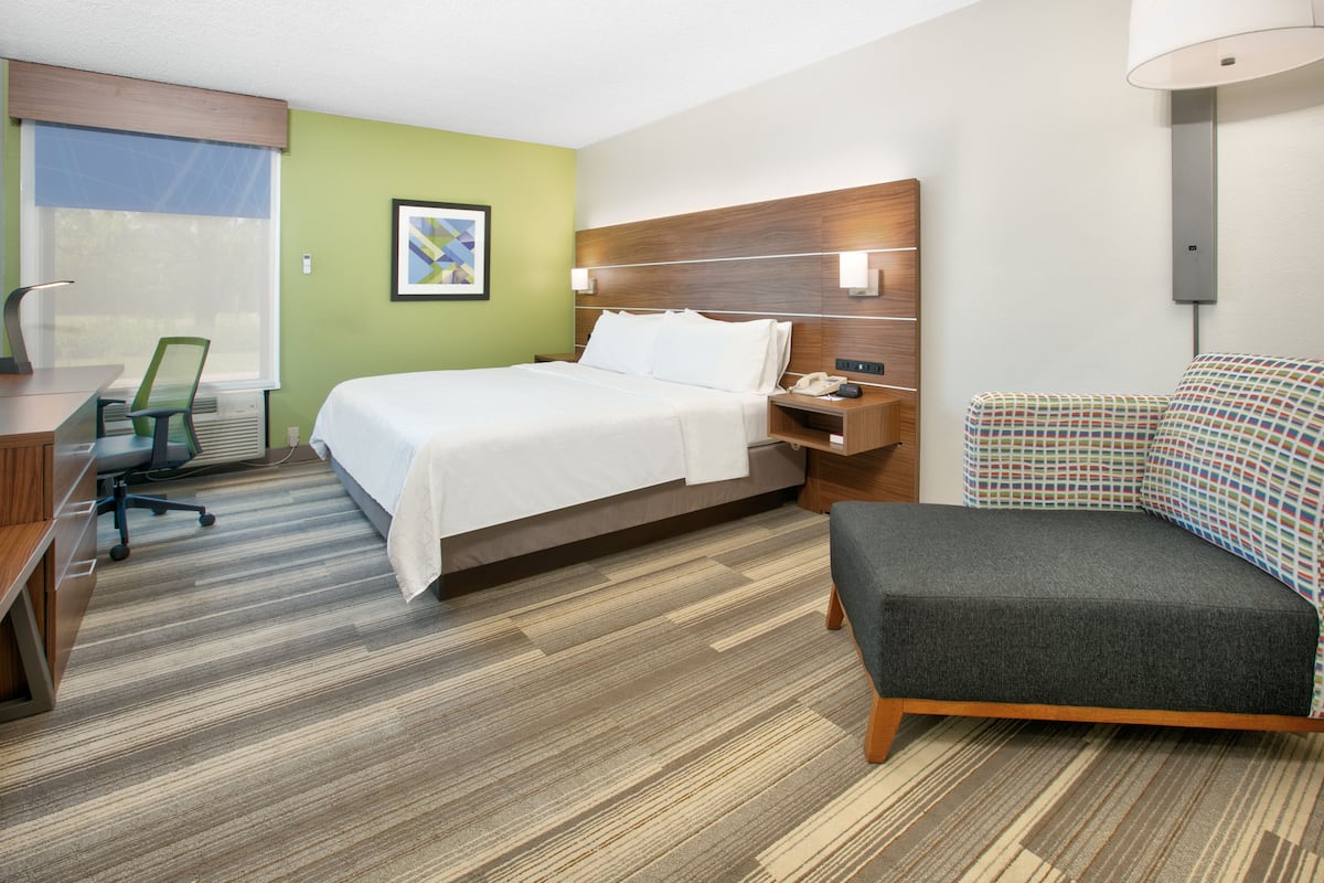 A hotel room with a bed, desk, chair, and sofa.