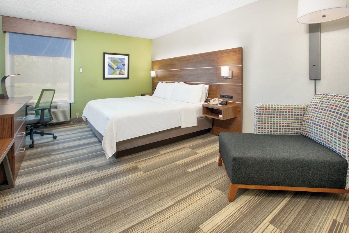 A hotel room with a bed, desk, chair, and a sofa.