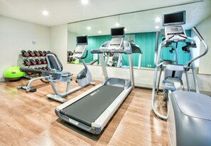 A gym with treadmills, elliptical machines, and a weight rack.