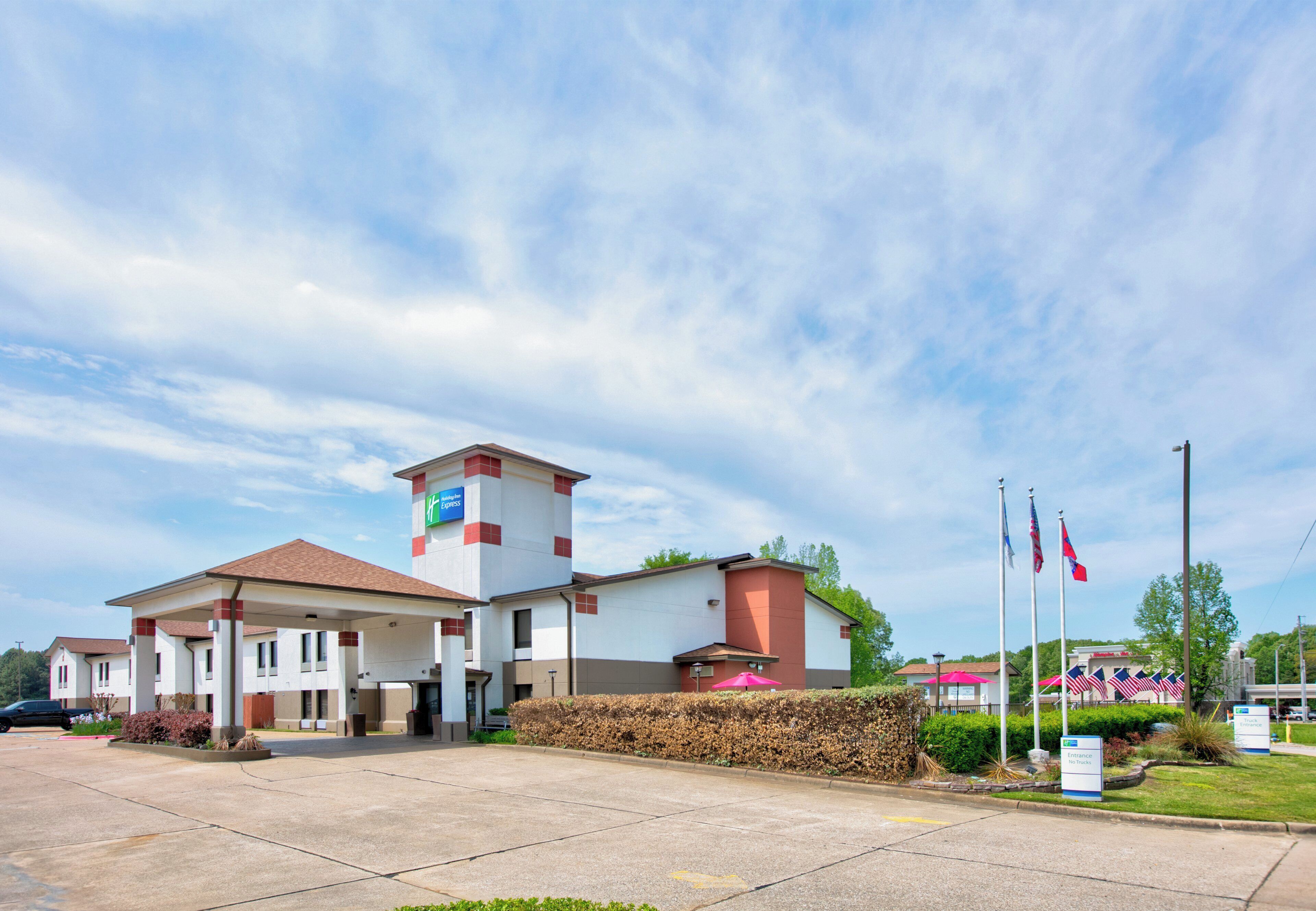 A hotel with a covered parking area, a small tower, and flags.