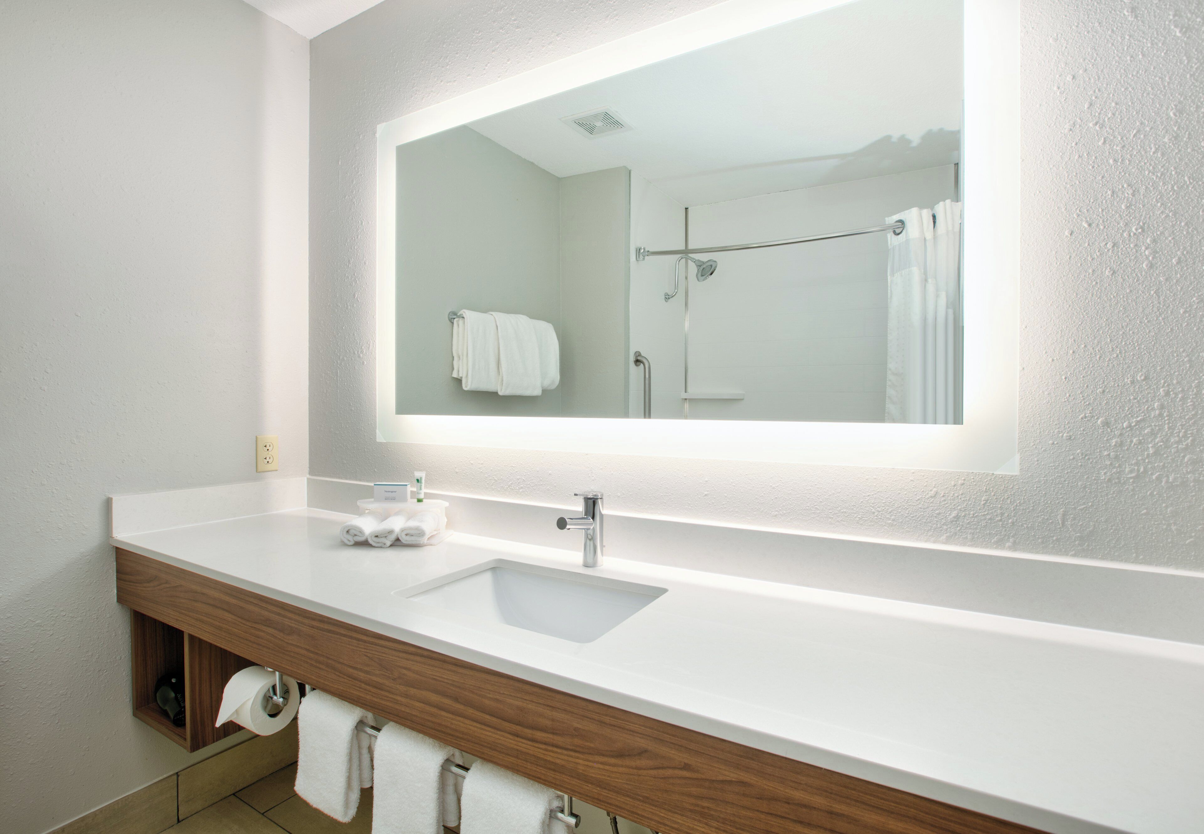 A bathroom with a white sink, a mirror, and a shower.
