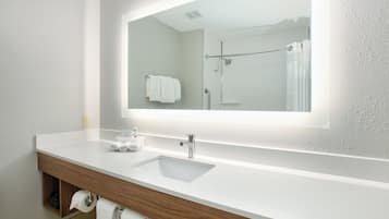 A bathroom with a white sink, a mirror, and a shower.