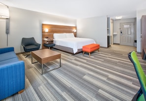 A hotel room with a bed, a desk, a chair, and a sofa.