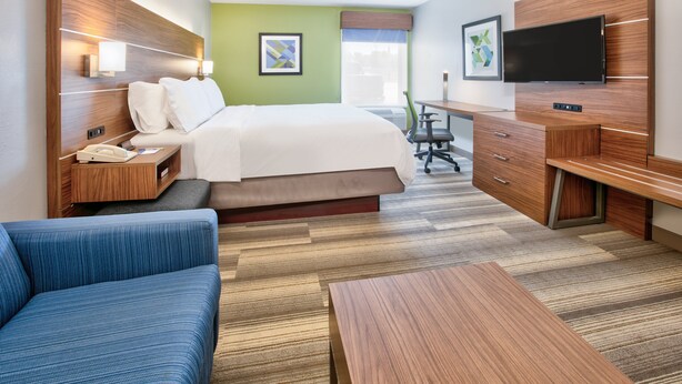A hotel room with a bed, a desk, a television, a blue sofa, and a wooden coffee table. - Holiday Inn Express Hope by IHG (Hope)