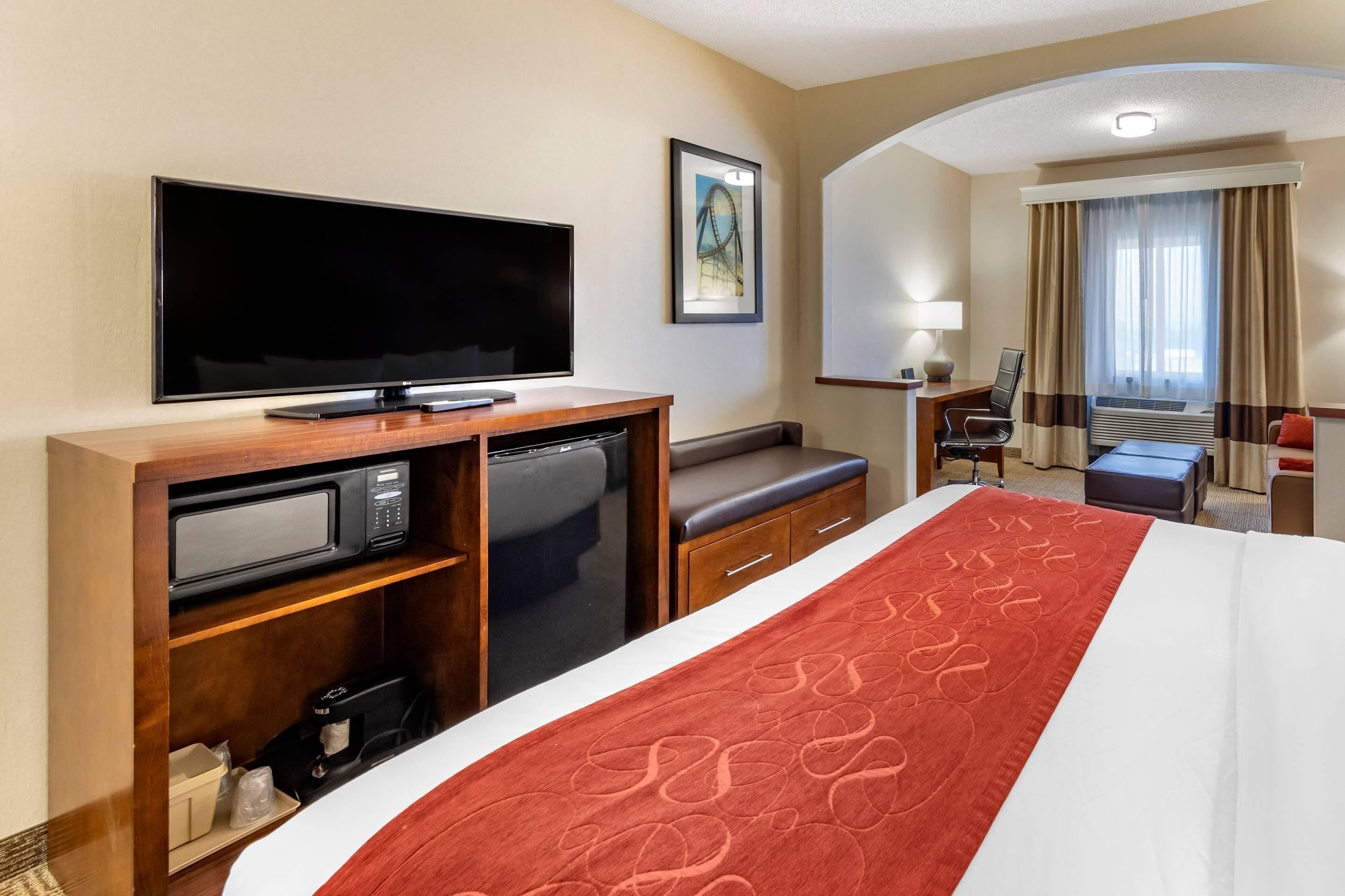A hotel room with a bed, a TV, a microwave, a desk, and a chair.