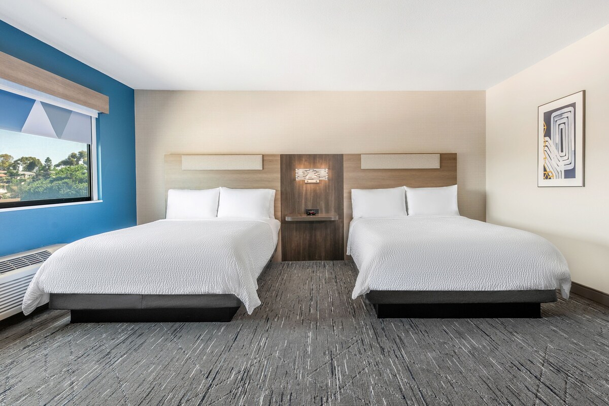 Une chambre d’hôtel avec deux lits, une grande fenêtre et une vue sur l’extérieur.