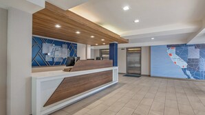 Una zona de recepción de diseño moderno, con un mostrador de madera, un panel en la pared con motivos geométricos azul y blanco, y un mapa colgado.