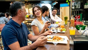 Un grupo de personas cenando en un restaurante con diversos platos y bebidas sobre la mesa.