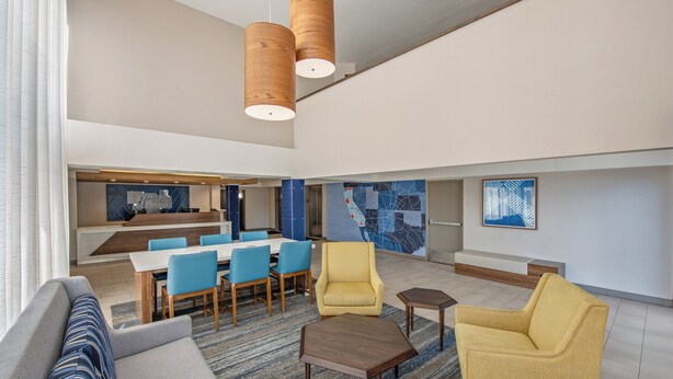 Un amplio hall de hotel con zona de comedor, asientos y decoración moderna.