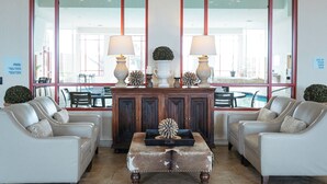 A lobby with two white leather sofas, a wooden coffee table, and a large window with a view of the pool. - Holiday Inn Express Hotel & Suites Olathe North by IHG (Olathe)