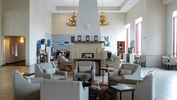 A spacious lobby with a fireplace, seating area, and modern chandeliers.