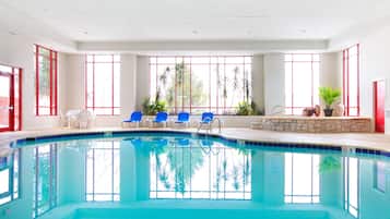 Een binnenzwembad, ligstoelen bij het zwembad