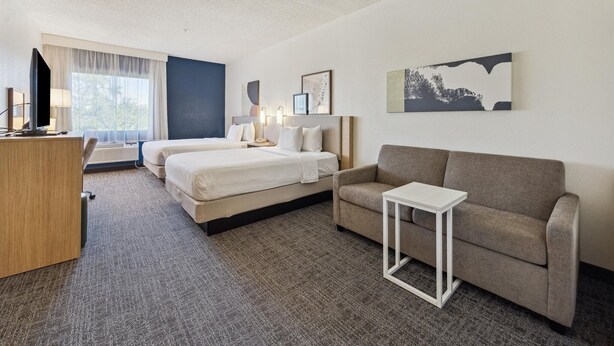 A hotel room with two beds, a sofa, a desk, and a TV. - Spark by Hilton Houston near the Galleria (Houston)