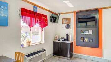 Una habitación con ventana, un televisor de pared, un armario con varios objetos y una pared con una cita motivacional.