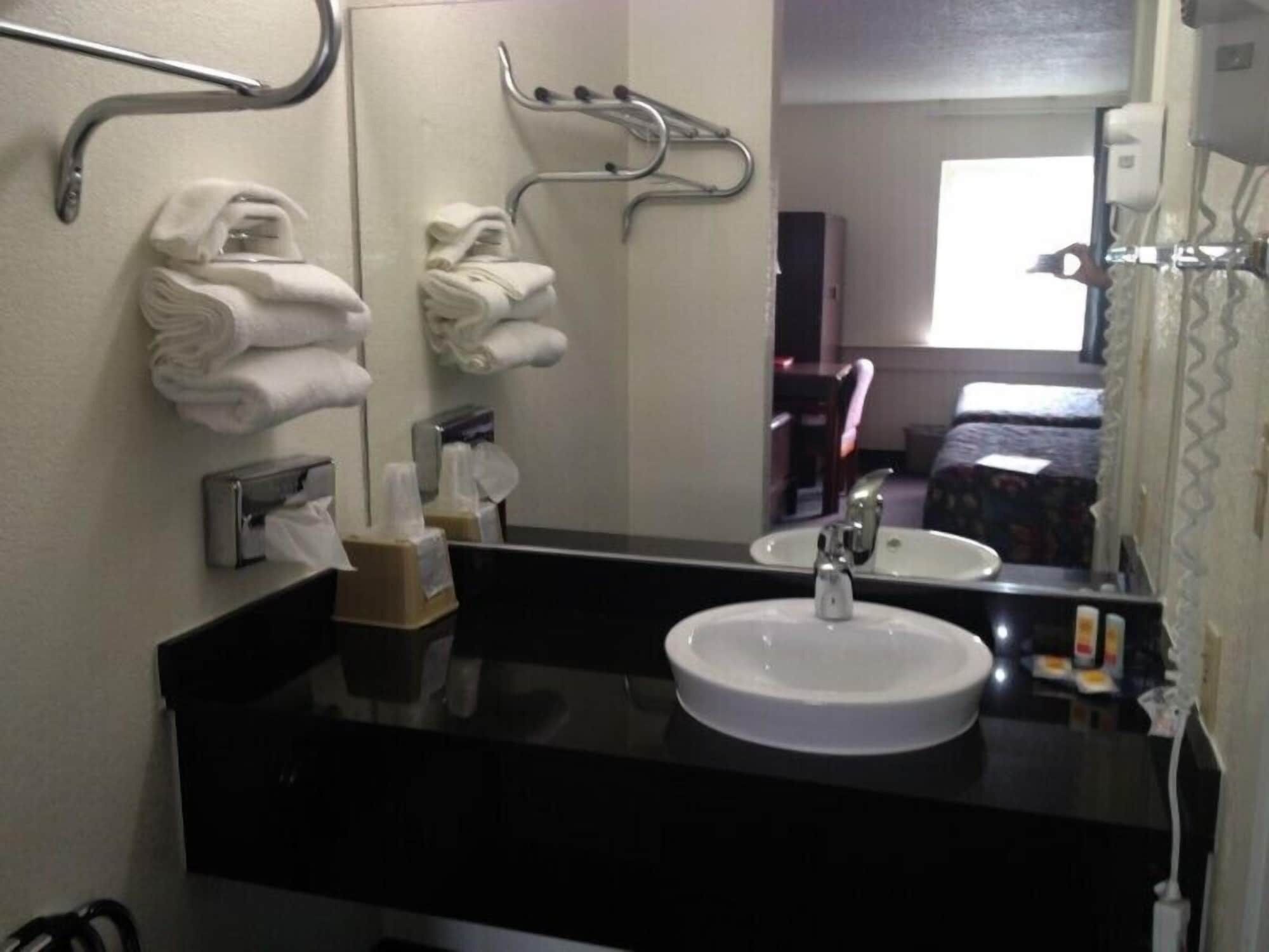 A hotel bathroom with a sink, towel rack, and mirror.