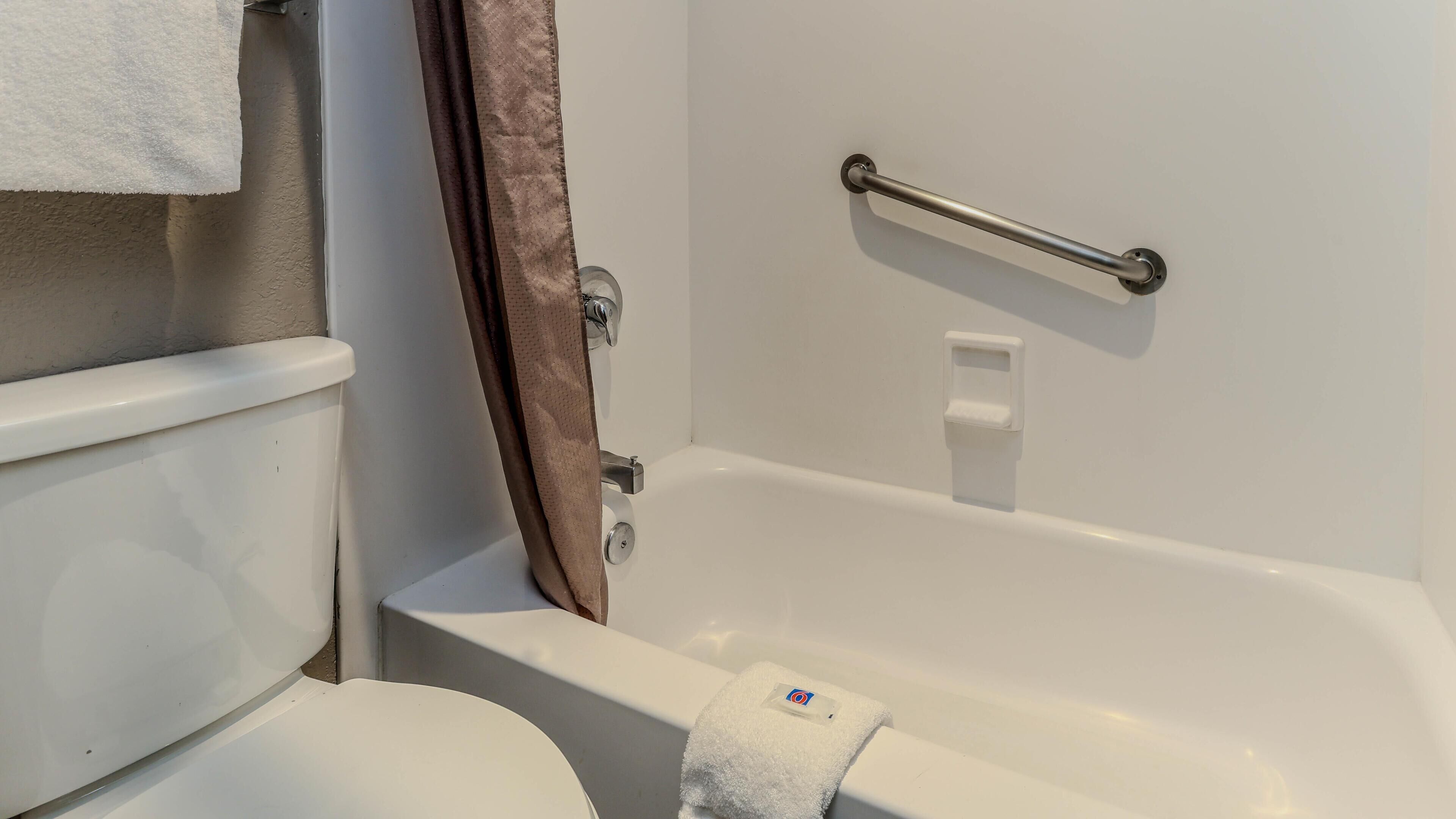 Une salle de bain avec une baignoire blanche, des toilettes et un rideau de douche.