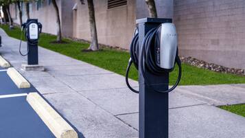 Estaciones de carga para vehículos eléctricos en una acera con un edificio al fondo.