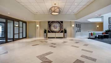 A spacious lobby with a modern chandelier, a reception desk, and a large wall mural.