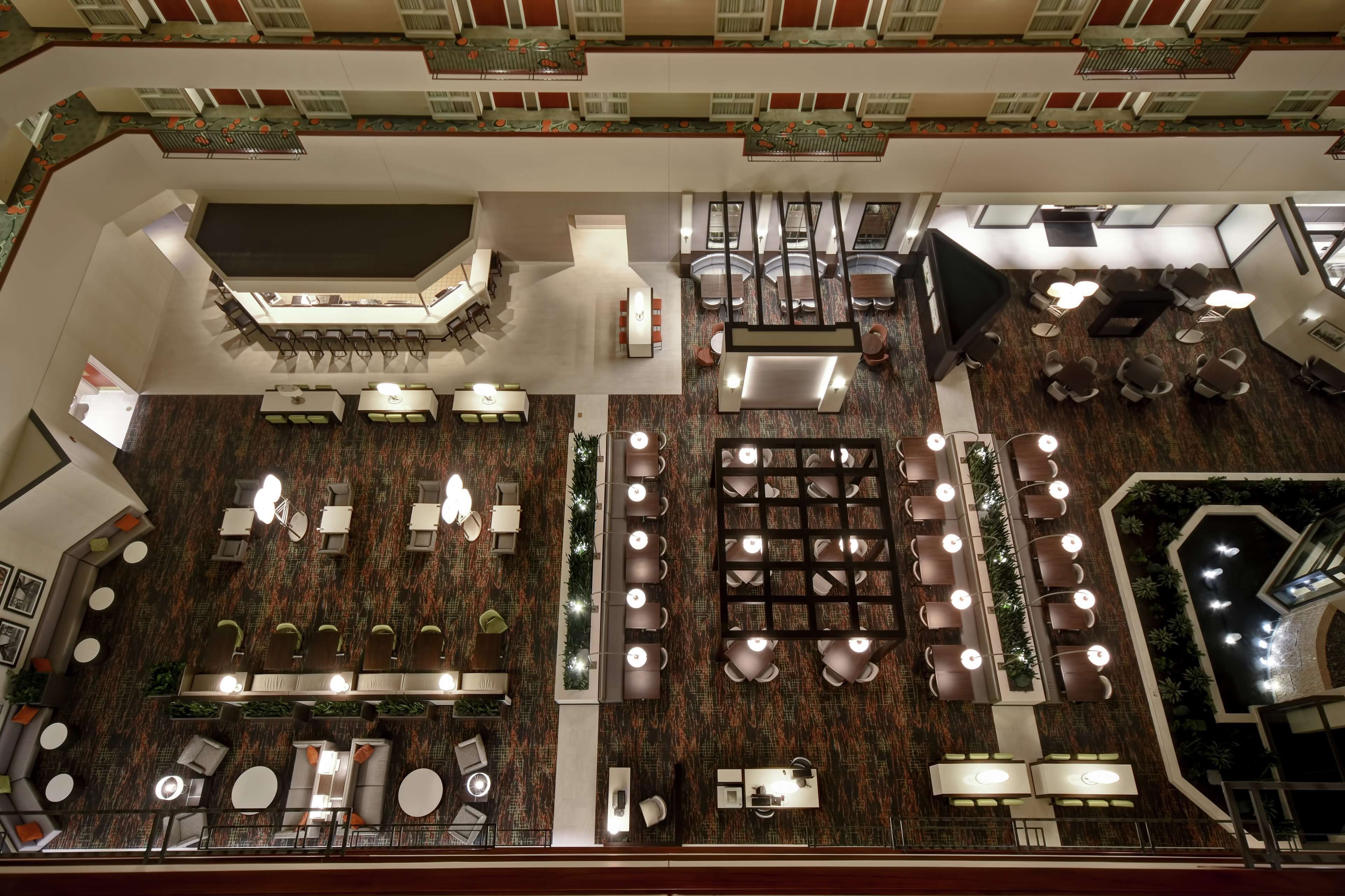 A spacious hotel lobby with multiple seating areas, a central staircase, and a decorative ceiling.