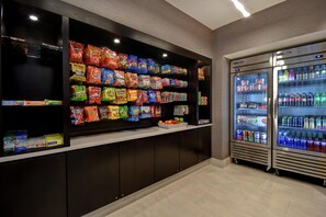 Un espace de vente proposant des collations et des boissons, avec différentes marques de chips et un rayon réfrigéré contenant des boissons en bouteille.