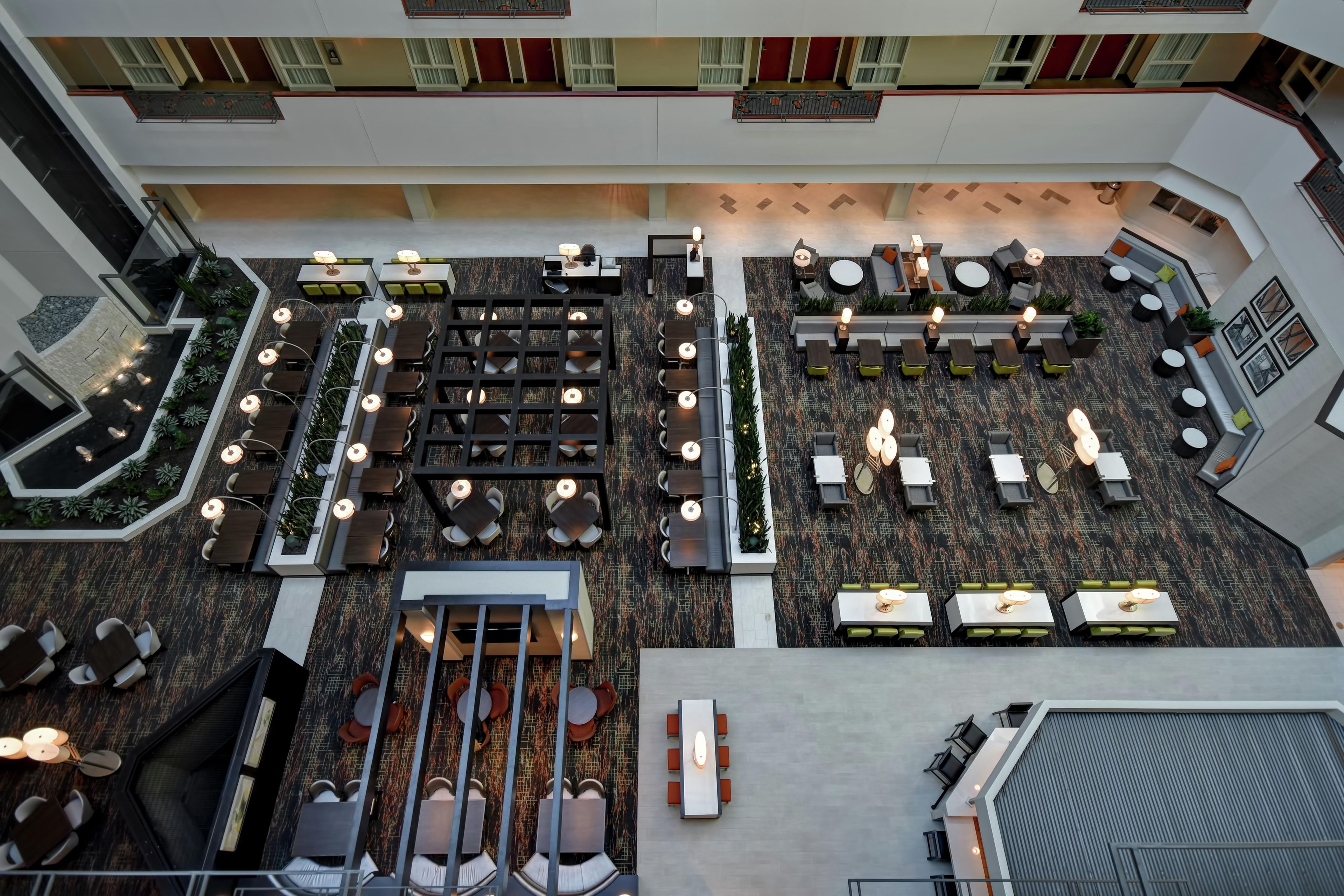 A multi-level indoor space with various seating arrangements, including tables and chairs, and a central area with a patterned floor.