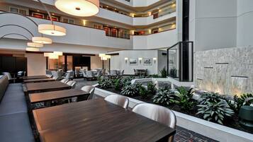 A multi-level hotel lobby with dining areas, a water feature, and a modern design.