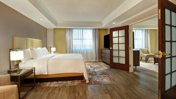 A hotel room with a large bed, bedside table, lamp, and a television.