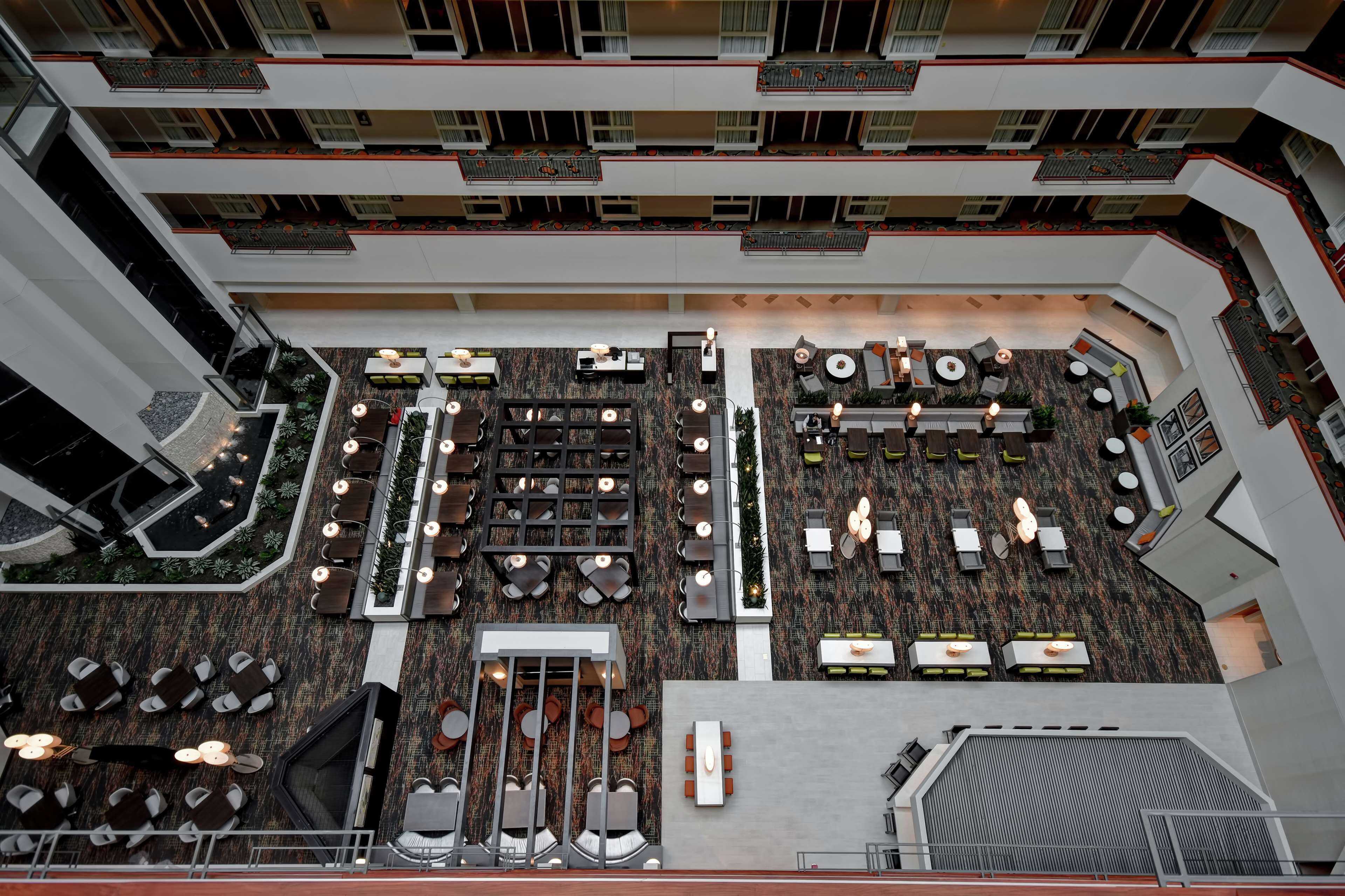 Un vestíbulo de hotel de varios niveles con diferentes zonas de estar, una escalera central y un suelo con diseño.
