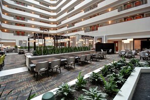 A multi-level hotel lobby with seating areas, a reception desk, and a TV screen. - Embassy Suites Little Rock (Little Rock)