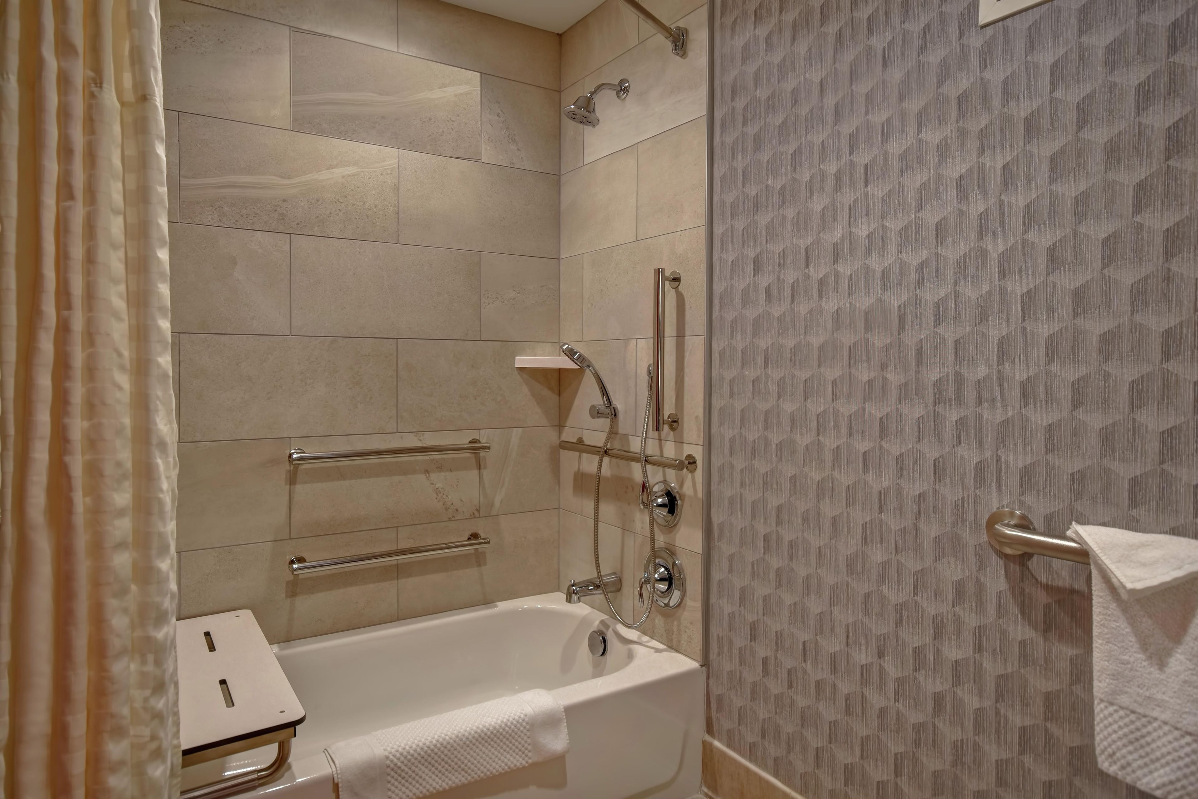 Un baño con bañera, ducha y barra de apoyo.