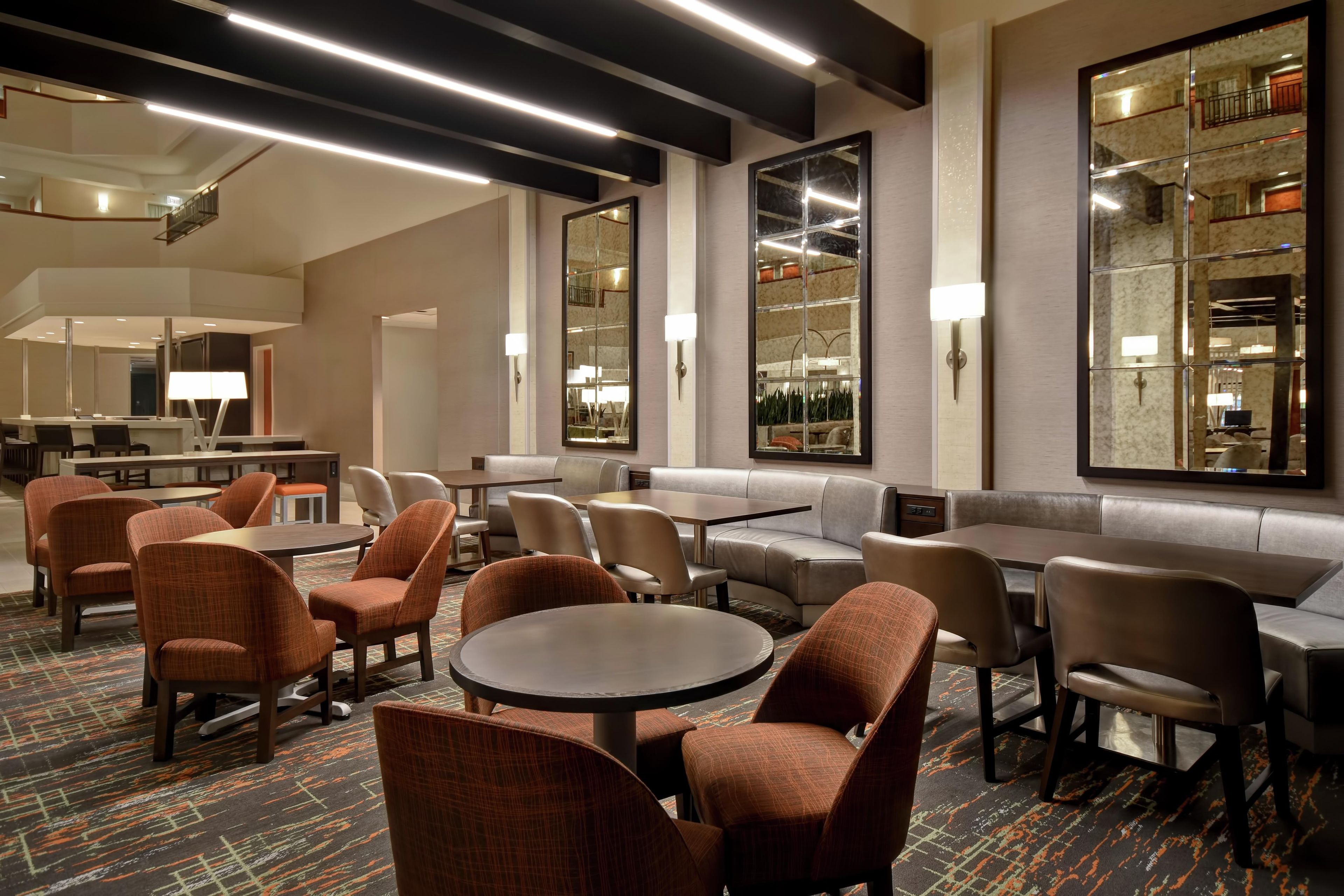 A hotel lobby with seating areas, tables, and a bar.
