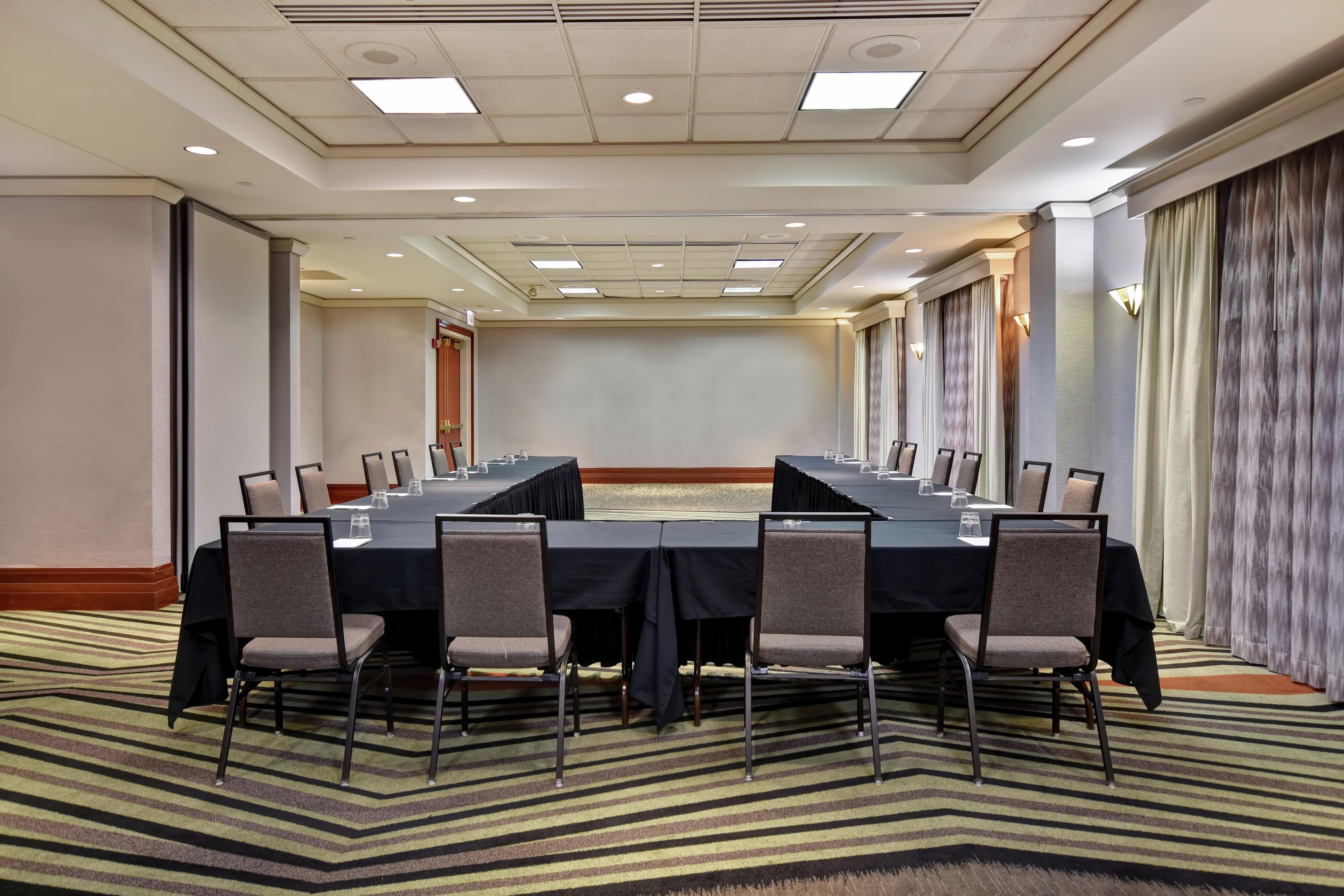 A conference room with a long table, chairs, and a carpeted floor.