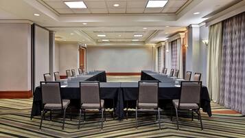 A conference room with a long table, chairs, and a carpeted floor.